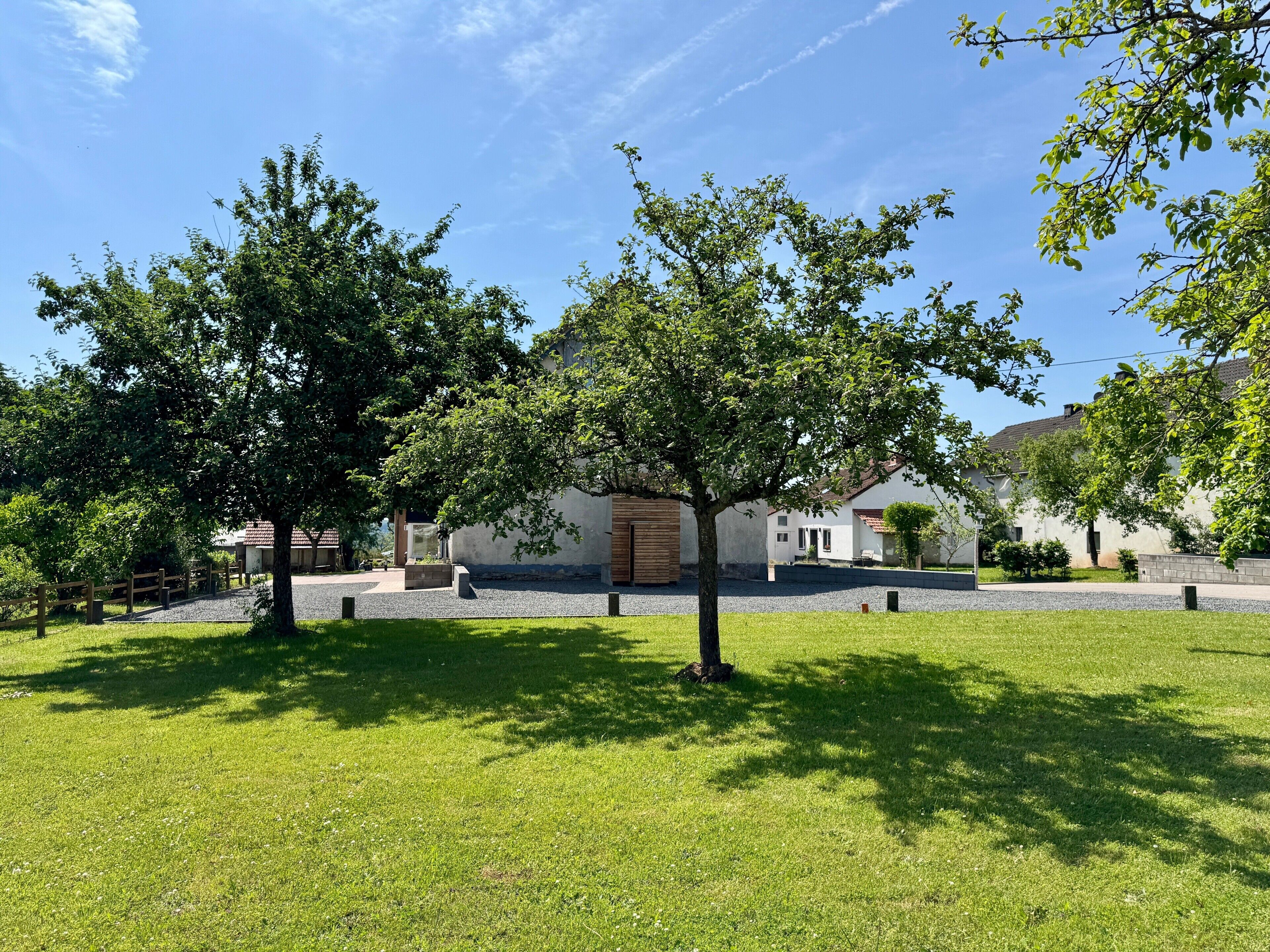 A residential property with a paved driveway, a wooden fence, and a grassy lawn.