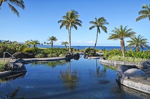 Relax by the ocean-view pool surrounded by lush greenery and palm trees, featuring a unique turtle-shaped design.