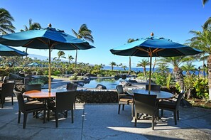 Relax in a tropical oasis with a poolside view of the ocean and distant mountains.