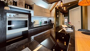 A modern kitchen with a built-in oven, a black countertop, and a wooden dining area. - Apartment 'The Rooftop Of Lot54' with Private Terrace, Private Garden and Wi-Fi (Feuerscheid)
