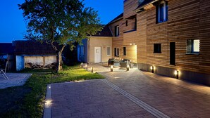 A modern house with a paved patio, a wooden exterior, and a well-lit outdoor area. - Apartment 'The Rooftop Of Lot54' with Private Terrace, Private Garden and Wi-Fi (Feuerscheid)
