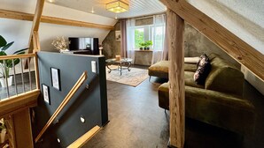 A loft-style living room with a staircase, a television, a sofa, and a dining table. - Apartment 'The Rooftop Of Lot54' with Private Terrace, Private Garden and Wi-Fi (Feuerscheid)