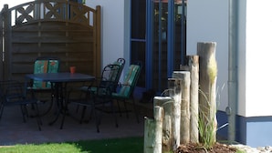 A house with a patio, outdoor seating, and a wooden fence. - 'Haus Windroos' with Private Terrace, Garden, and Wi-Fi (Zingst)