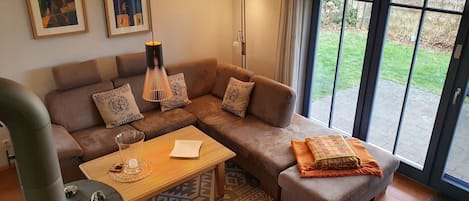 A modern living room with a sectional sofa, a coffee table, a lamp, and a view through a glass door.