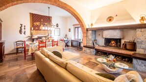 A cozy living room with a stone fireplace, a sofa, and a dining area with a table and chairs.