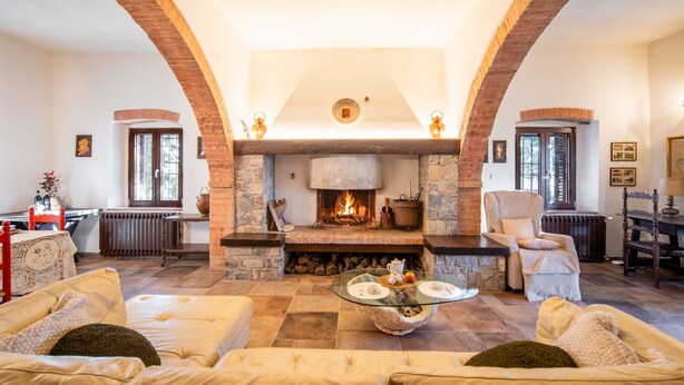 A cozy living room with a stone fireplace, two sofas, a round coffee table, and a dining area with a table and chairs.