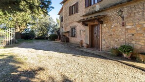 A stone building with a gravel driveway and a wooden gate.