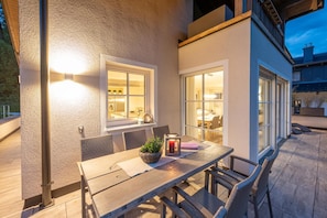 An outdoor patio with a wooden table, wicker chairs, and a lantern. - Apartment 'Ronacher' with Mountain View, Private Terrace and Wi-Fi (Eben im Pongau)