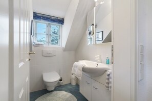 Ein Badezimmer mit Toilette, Waschbecken und Fenster.