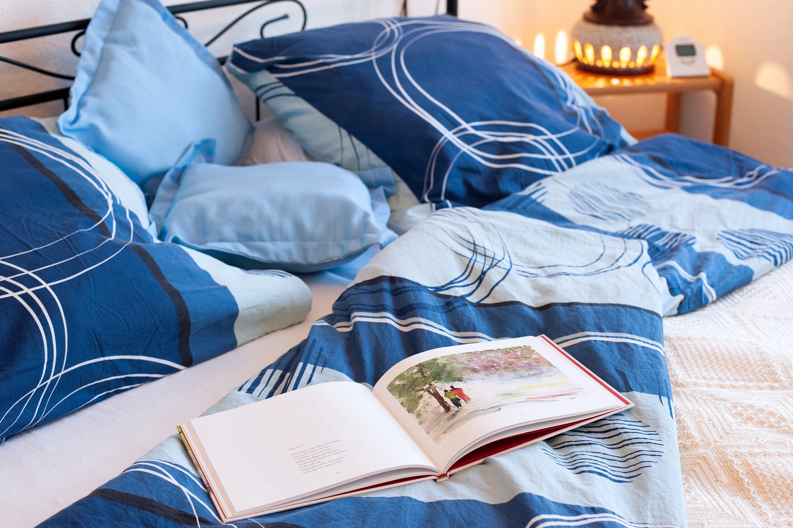 A bed with blue bedding and a book on it.