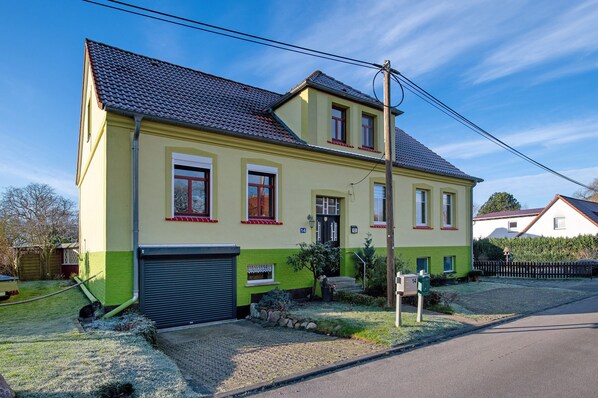 Une maison à deux étages avec un garage, un petit jardin et un ciel dégagé.
