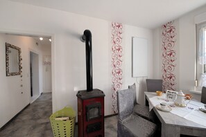 A room with a wood-burning stove, a dining table with a sign, and a patterned wall. - Apartment 'Familienfreundliche' with Private Garden and Wi-Fi (Kenz-Küstrow)