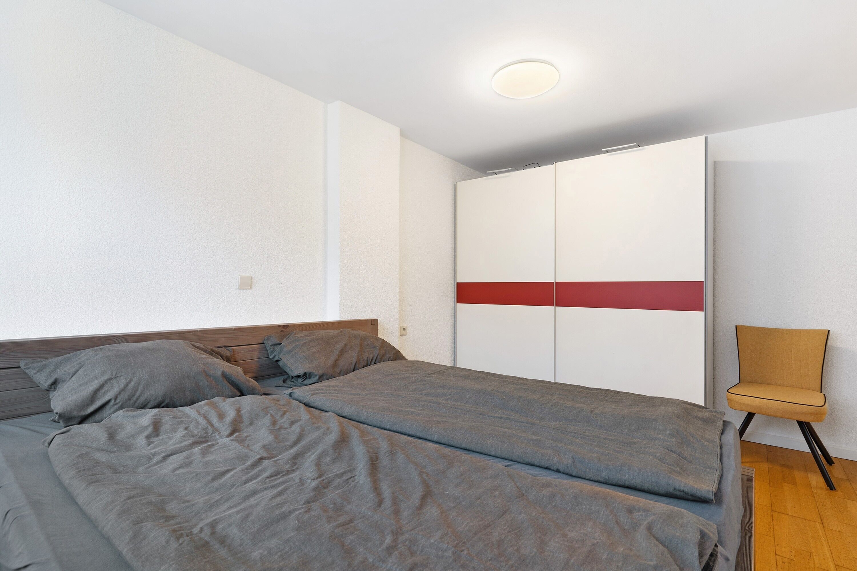 A bedroom with two beds, a wardrobe, and a chair.