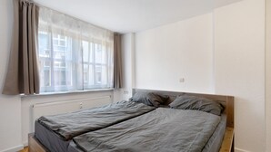 Een slaapkamer met een bed, raam en radiator.