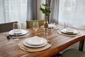 A wooden dining table set with plates, cutlery, and a glass vase with a plant. - Apartment 'Merlin' with Wi-Fi (Ettenheim)