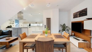 A modern kitchen with white cabinets, a central island, and a dining area with a wooden table and chairs.