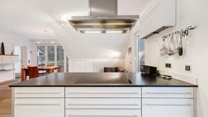 A modern kitchen with a central island, white cabinetry, and a stainless steel range hood.