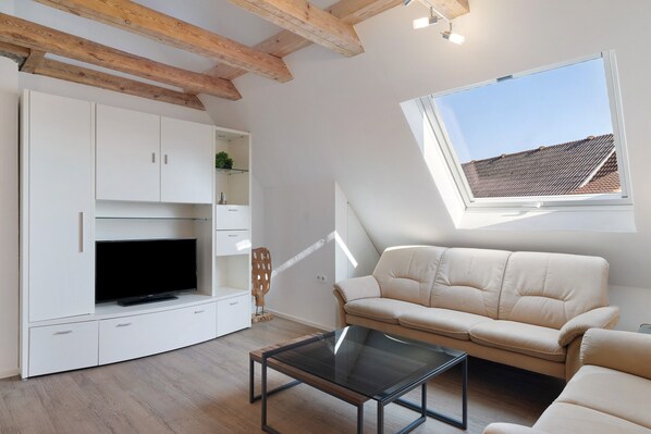 A modern living room with a TV, sofa, and glass coffee table.