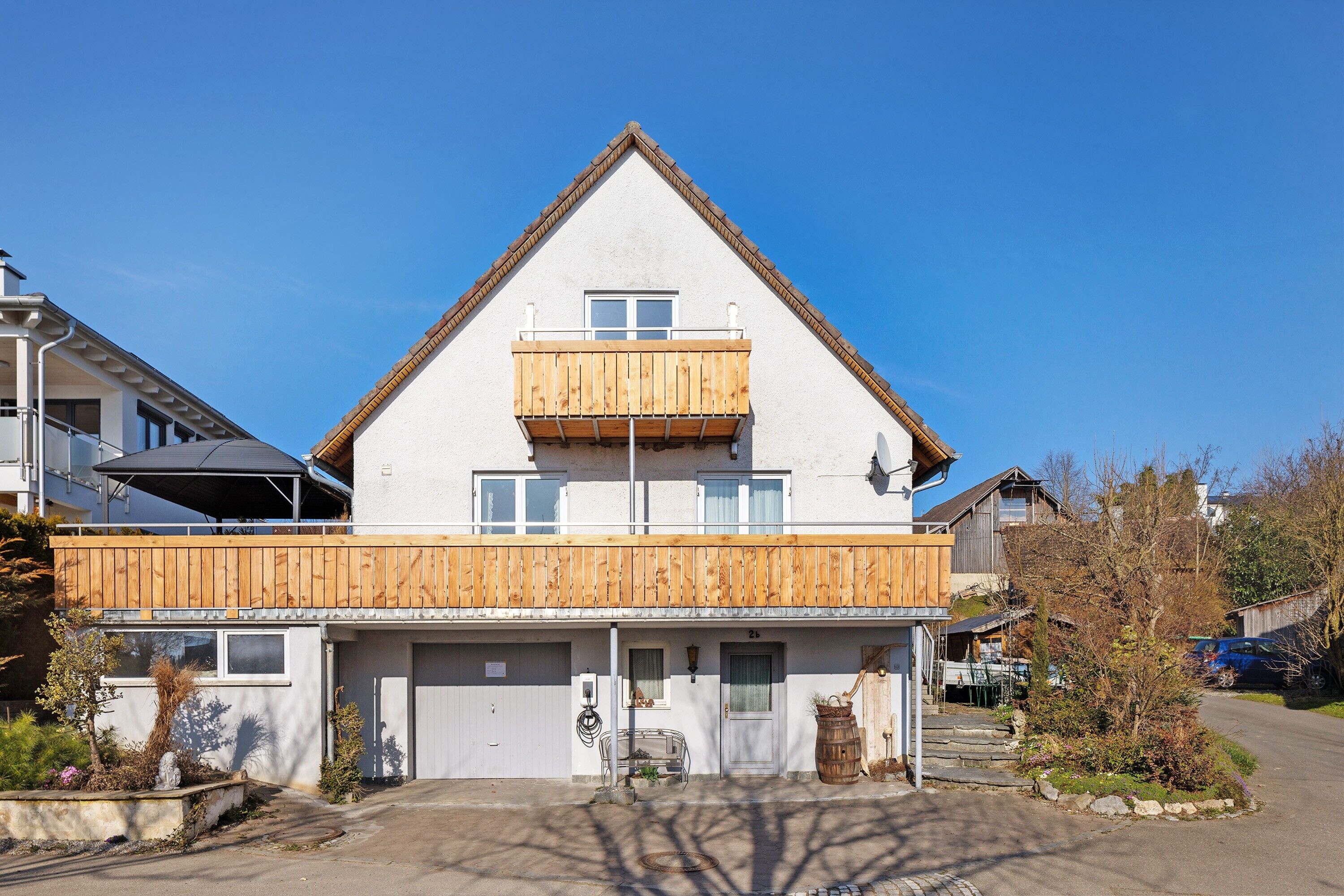 Ein zweistöckiges Haus mit Holzbalkon, Garage und blauem Himmel.