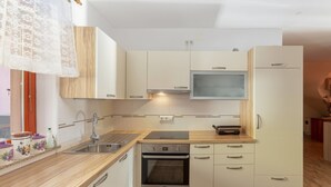 Een kleine keuken met een inbouwoven, een magnetron en een spoelbak.