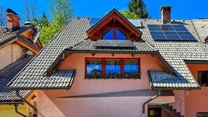 Een huis met een schuin dak, zonnepanelen en een balkon met plantenpotten.