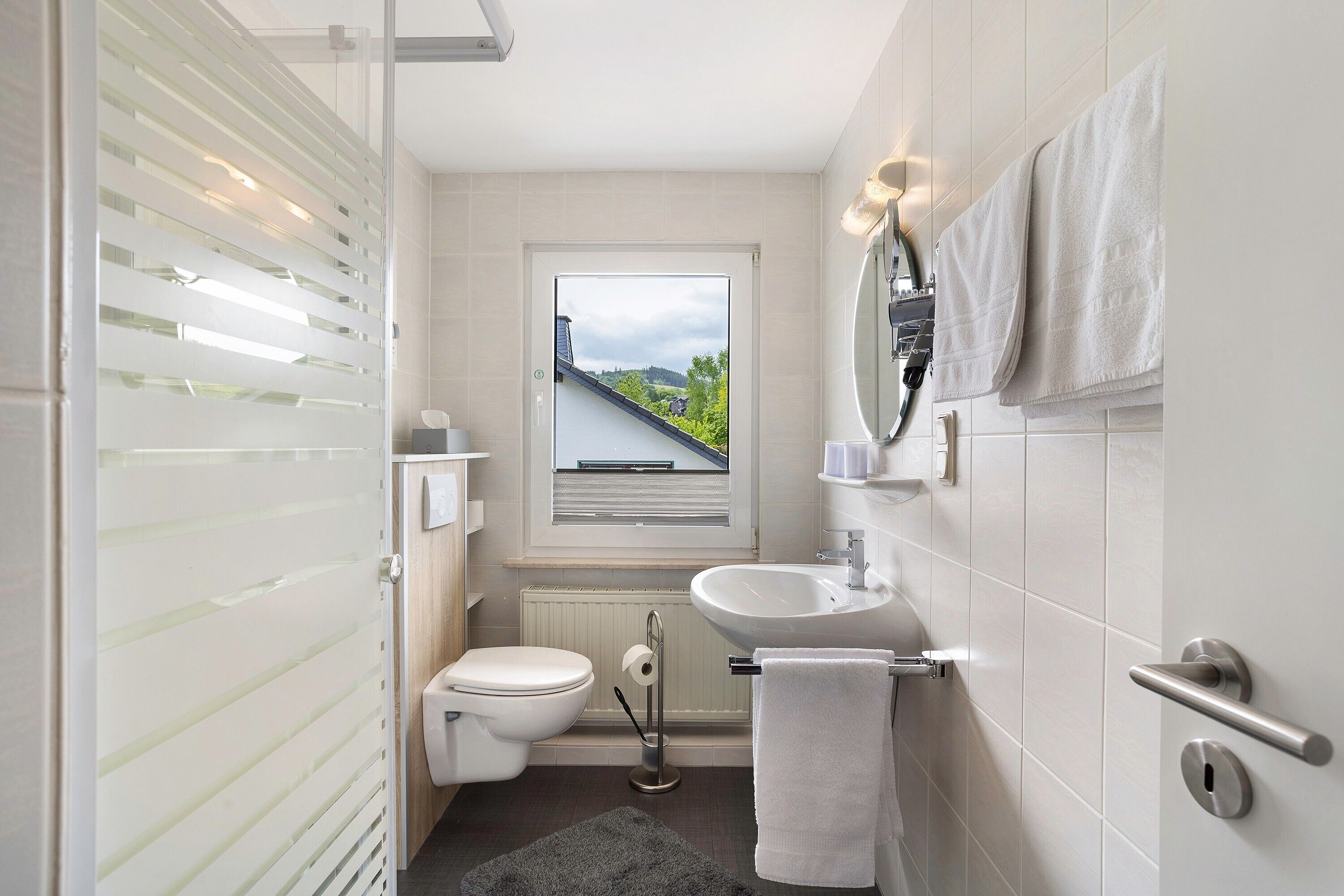 Une salle de bain moderne équipée de toilettes, d’un lavabo et d’un porte-serviettes.