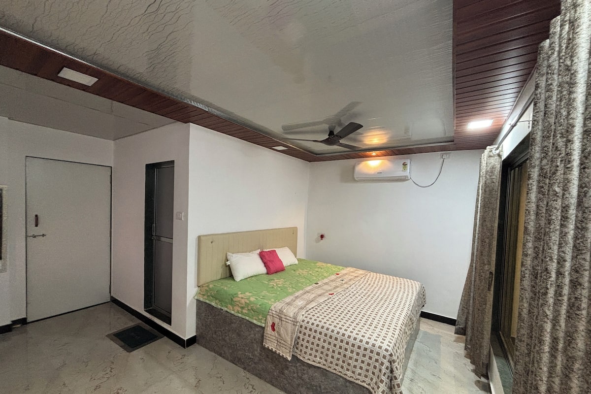 A bedroom with a bed, a ceiling fan, an air conditioning unit, and a door.