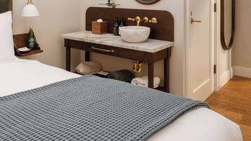 Une chambre d’hôtel comprenant un lit, une table de chevet avec une lampe, un miroir, une salle de bain avec un lavabo et une porte.