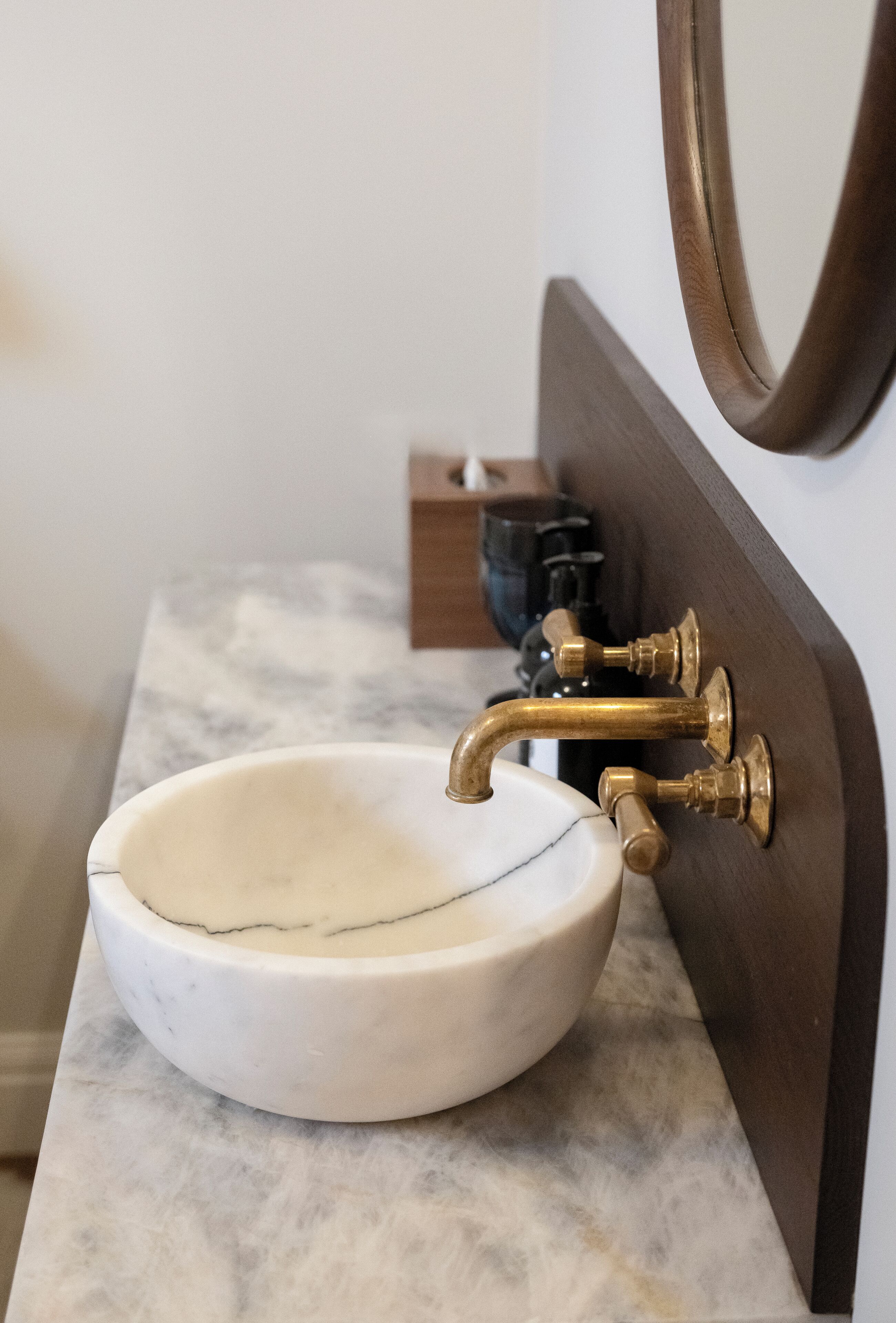 A bathroom sink with a marble countertop and a brass faucet.