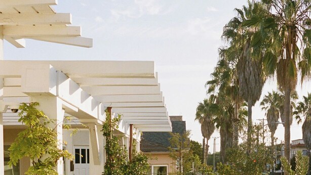 A wooden deck with outdoor seating, large planters, and a white pergola structure. - Gjelina Hotel (Venice)