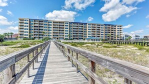 A hotel with a long wooden boardwalk leading to a large building with multiple balconies.