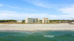 Un hotel frente a la playa con varias edificaciones, una playa de arena y el océano.