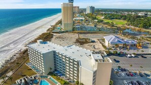Un hotel con piscina, vista a la playa y zona de estacionamiento.