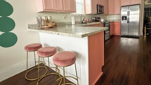 Una cocina con armarios rosa, un refrigerador de acero inoxidable y una encimera de mármol.