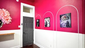 Un pasillo con una decoración en rojo y blanco, suelo de madera, una puerta y obras de arte colgadas en la pared.