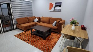Un salon moderne comprenant un canapé d’angle, une table basse, une table à manger avec des chaises et un tapis à motifs.