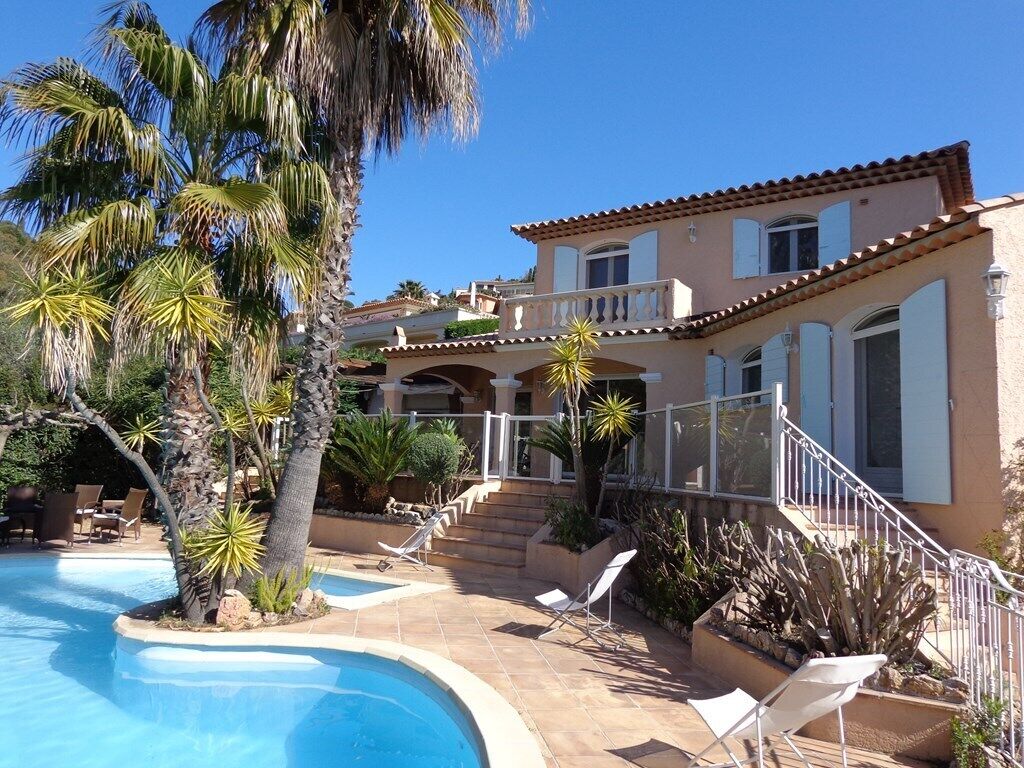 A resort with a swimming pool, palm trees, and a two-story building with balconies.