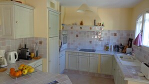 A kitchen with white cabinets, a tiled backsplash, a sink, and a window with a towel hanging.