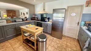 A modern kitchen with grey cabinets, a stainless steel refrigerator, and a wooden island with a trash bin. - VILLA WITH SWIMMING POOL TO RENT FOR 6 PEOPLE, QUIET AREA 1.2 KM FROM THE BEACH (STE MAXIME)