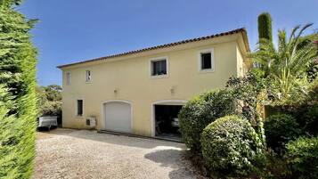 Un bâtiment à deux étages, doté d’une façade beige, d’un toit en tuiles et d’une allée gravillonnée.