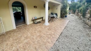 A covered patio area with a tiled floor, a bench, and a table with chairs. - VILLA WITH SWIMMING POOL TO RENT FOR 6 PEOPLE, QUIET AREA 1.2 KM FROM THE BEACH (STE MAXIME)