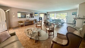 A spacious living room with a round glass coffee table, leather sofas, and a dining area with a curved bench. - VILLA WITH SWIMMING POOL TO RENT FOR 6 PEOPLE, QUIET AREA 1.2 KM FROM THE BEACH (STE MAXIME)