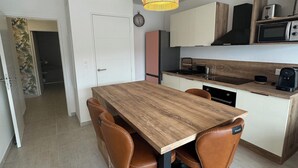 A modern kitchen with a wooden dining table, four chairs, and a hanging light fixture. - Cosy apartment in new residence  (Propriano)