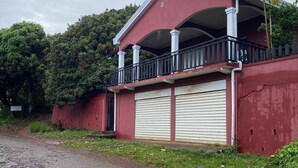 A building with a red facade, a covered balcony, and closed garage doors.