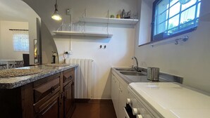 Une cuisine dotée d’un plan de travail en granit, d’un four encastré, d’un évier et d’une fenêtre avec une horloge.