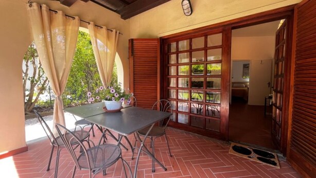 Une terrasse extérieure avec une table et des chaises, une porte en bois et une vue sur le jardin.