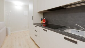 A modern kitchen with white cabinets, a black countertop, and a stainless steel sink. - GuestHost - Primaticcio M1 Modern and Bright Apartment (Milano)