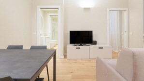 A modern living room with a flat-screen TV, a dining table, and a sofa. - GuestHost - Primaticcio M1 Modern and Bright Apartment (Milano)