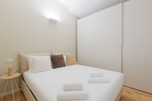 A modern bedroom with a large bed, bedside lamps, and a nightstand.