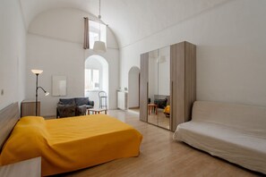 Ein modernes Hotelzimmer mit Bett, einer Sitzecke, einem Schreibtisch und einem Spiegel.